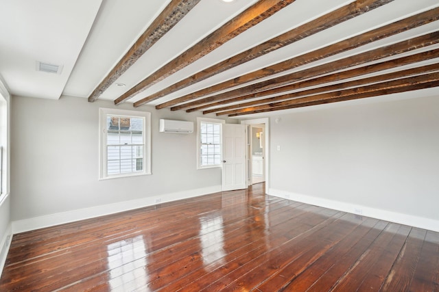 empty room featuring a wall unit AC, baseboards, visible vents, and dark wood-style flooring