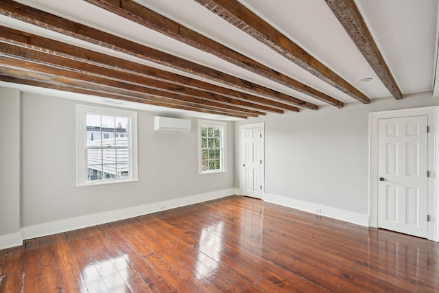 empty room with beamed ceiling, dark wood-type flooring, a wall mounted AC, and baseboards