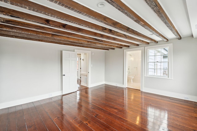 interior space featuring baseboards, dark wood finished floors, and beam ceiling