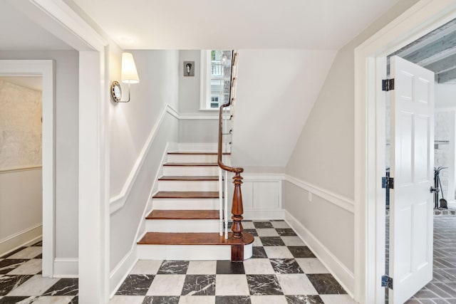 stairway with a wainscoted wall and a decorative wall