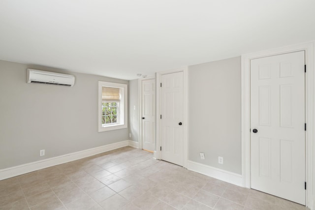 unfurnished bedroom featuring a wall unit AC and baseboards