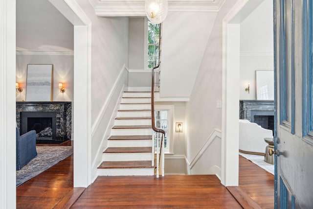 stairs with a fireplace, crown molding, and wood finished floors