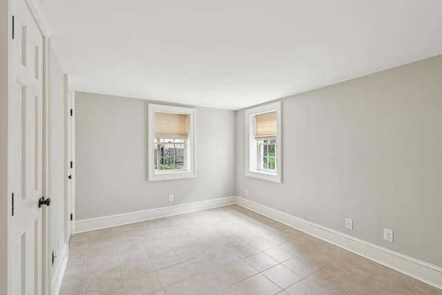 spare room featuring baseboards and light tile patterned flooring