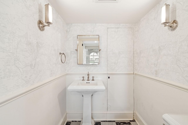 bathroom featuring toilet, visible vents, and a sink