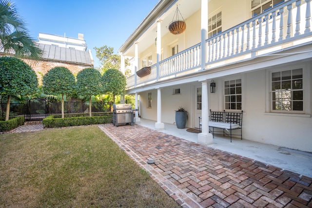 exterior space featuring a balcony, fence, a yard, a patio area, and stucco siding