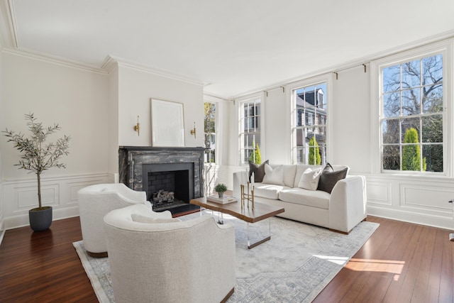 living area featuring a wainscoted wall, crown molding, dark wood finished floors, a decorative wall, and a high end fireplace