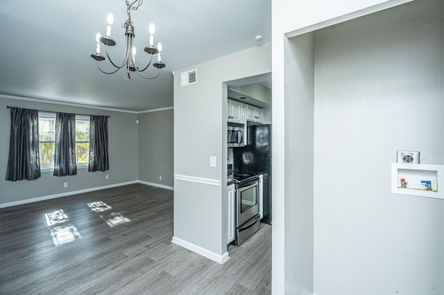 kitchen with crown molding, a chandelier, wood-type flooring, white cabinets, and appliances with stainless steel finishes