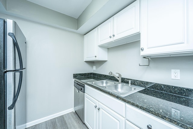 kitchen featuring white cabinets, sink, dark stone countertops, appliances with stainless steel finishes, and light hardwood / wood-style floors