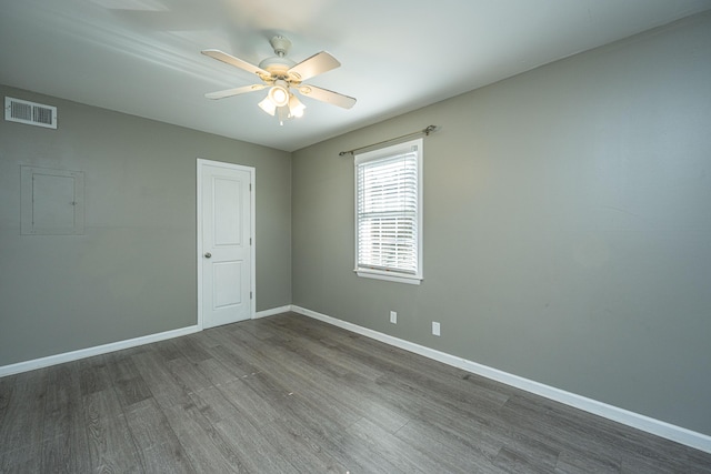 unfurnished room featuring electric panel, ceiling fan, and dark hardwood / wood-style floors