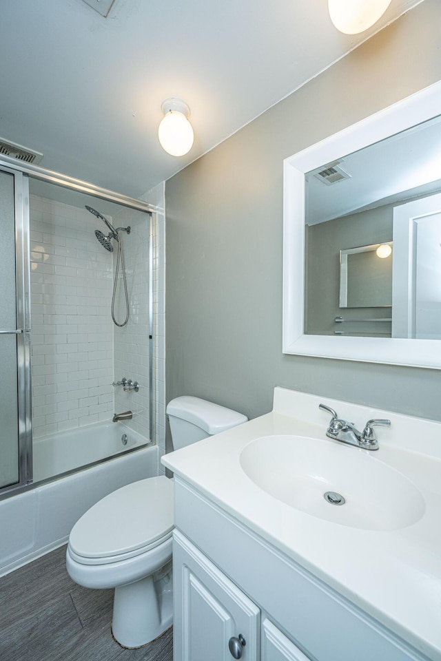 full bathroom with combined bath / shower with glass door, vanity, and toilet