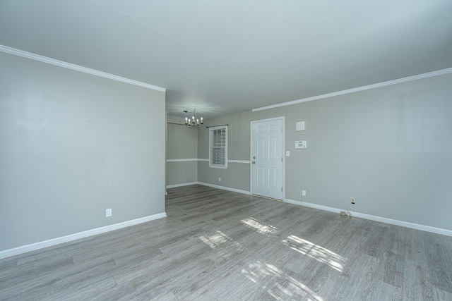 unfurnished room featuring crown molding, light hardwood / wood-style flooring, and an inviting chandelier