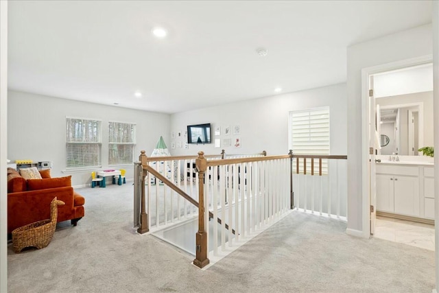 hallway with sink and light colored carpet