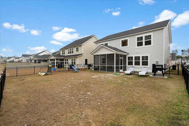 rear view of property with a lawn, a sunroom, and a playground