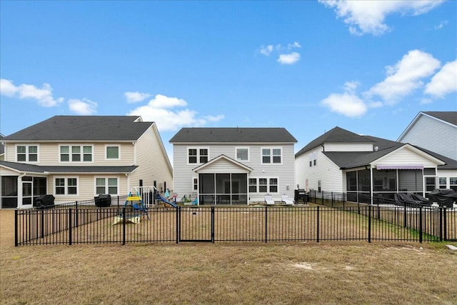 rear view of house with a yard, a playground, and a sunroom