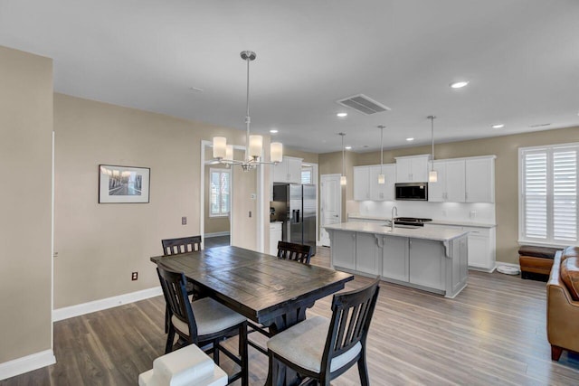 dining room featuring a wealth of natural light, wood finished floors, visible vents, and baseboards