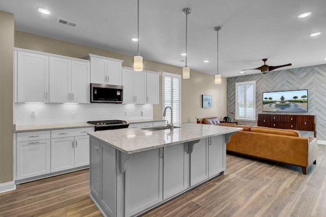 kitchen with a wealth of natural light, appliances with stainless steel finishes, open floor plan, a sink, and light wood-type flooring