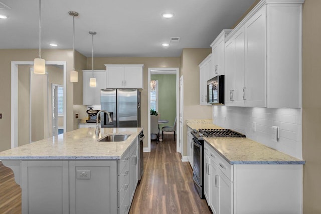 kitchen with white cabinets, dark wood-style floors, appliances with stainless steel finishes, a sink, and backsplash