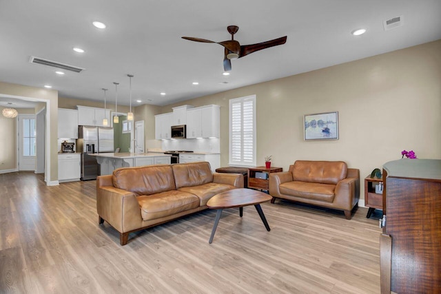 living area featuring light wood-type flooring, ceiling fan, visible vents, and recessed lighting