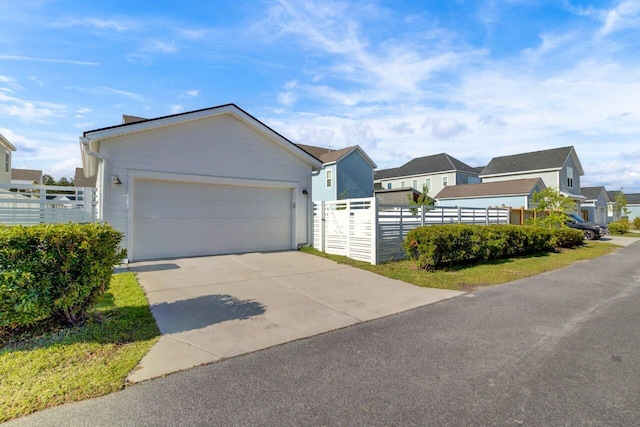 ranch-style home with an attached garage, a fenced front yard, a residential view, and concrete driveway