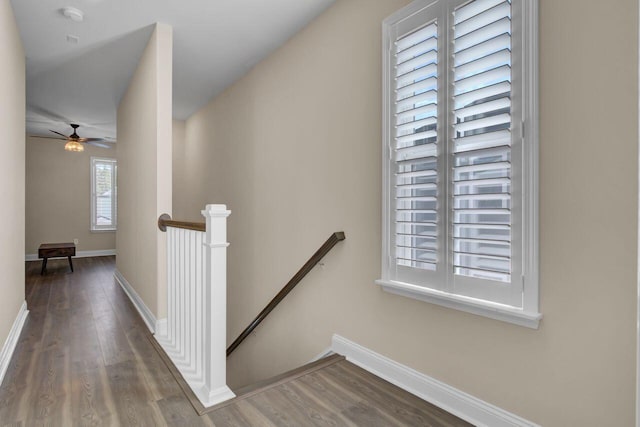 corridor with wood finished floors, an upstairs landing, and baseboards