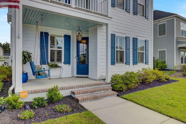 view of exterior entry with covered porch and a balcony