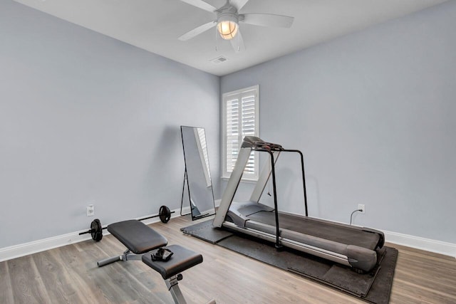 exercise room with a ceiling fan, visible vents, baseboards, and wood finished floors