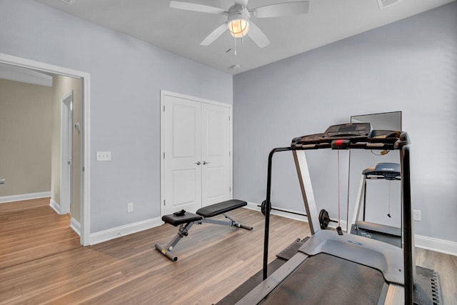 workout area featuring ceiling fan, wood finished floors, and baseboards