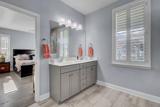 ensuite bathroom with ensuite bathroom, double vanity, a sink, and baseboards