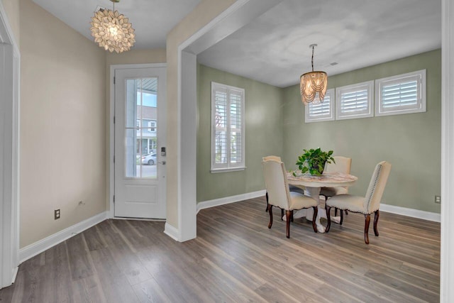 dining space with baseboards, a notable chandelier, and wood finished floors