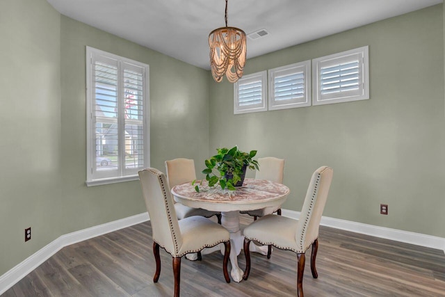 dining space featuring visible vents, a notable chandelier, baseboards, and wood finished floors