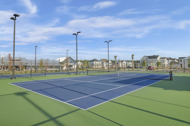 view of tennis court featuring fence and a residential view