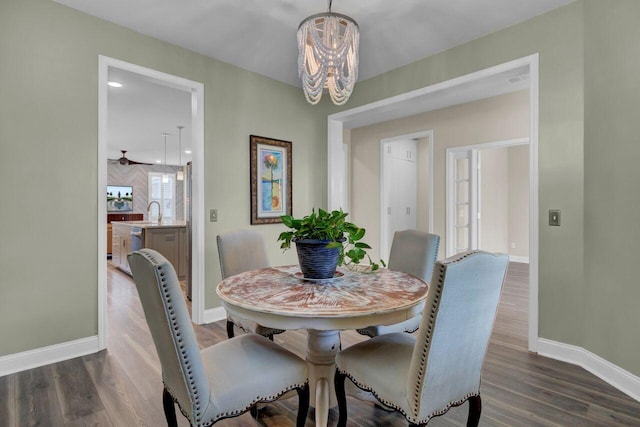 dining space featuring baseboards, a chandelier, and dark wood-style flooring