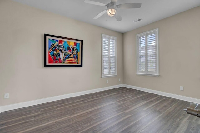 empty room featuring a ceiling fan, dark wood-style flooring, visible vents, and baseboards