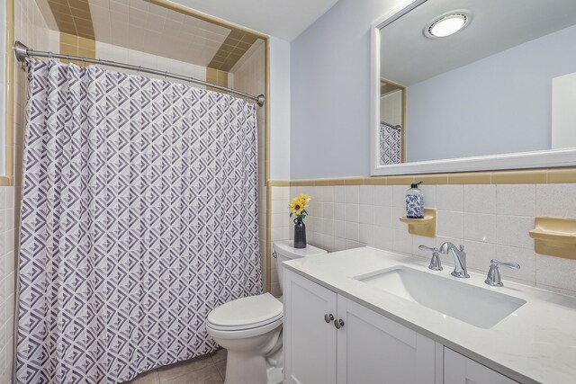 bathroom with tile patterned floors, vanity, toilet, and tile walls