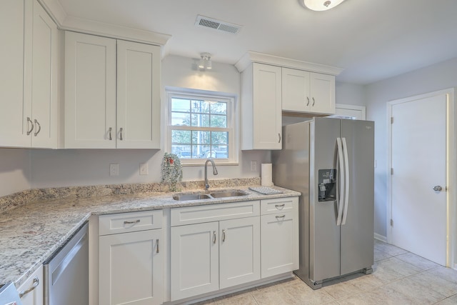 kitchen with white cabinets, sink, light tile patterned floors, light stone counters, and stainless steel appliances