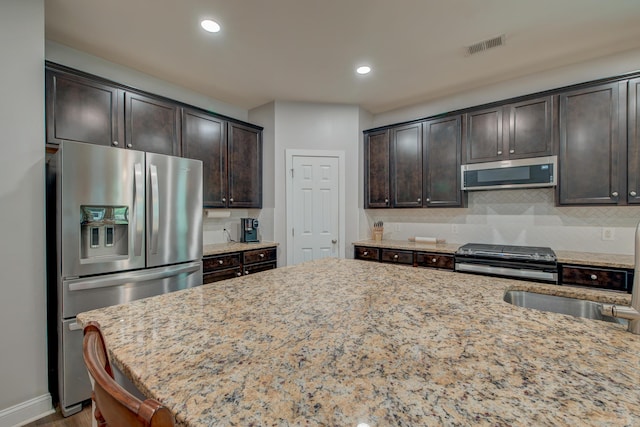 1589 Seabago Dr, Charleston, SC 29414 - kitchen featuring stainless steel appliances, light stone countertops, dark brown cabinets, decorative backsplash, and recessed lighting