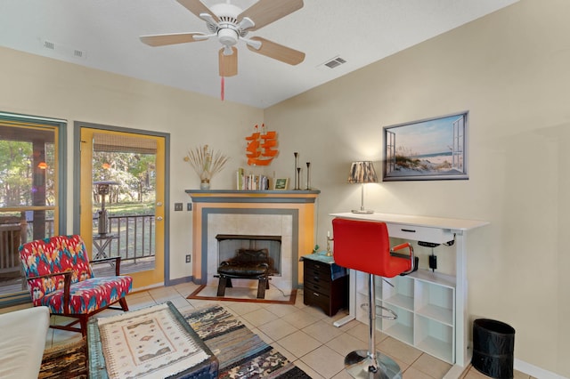 living room with light tile patterned floors, a textured ceiling, a tile fireplace, and ceiling fan