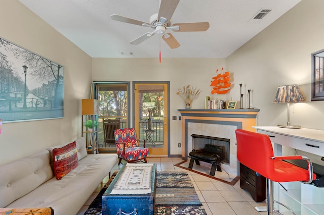 tiled living room with a textured ceiling, a fireplace, and ceiling fan