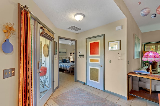 corridor featuring a textured ceiling and light tile patterned floors