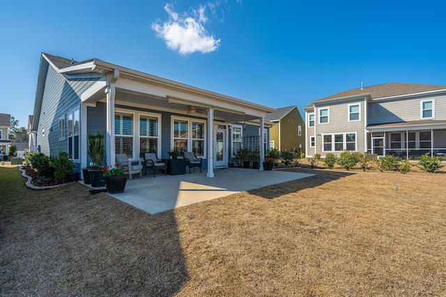 back of property with ceiling fan, a yard, and a patio