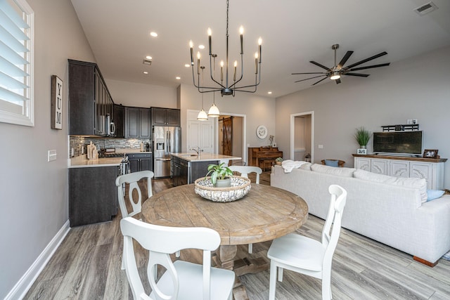 dining space featuring sink, ceiling fan with notable chandelier, and light hardwood / wood-style flooring