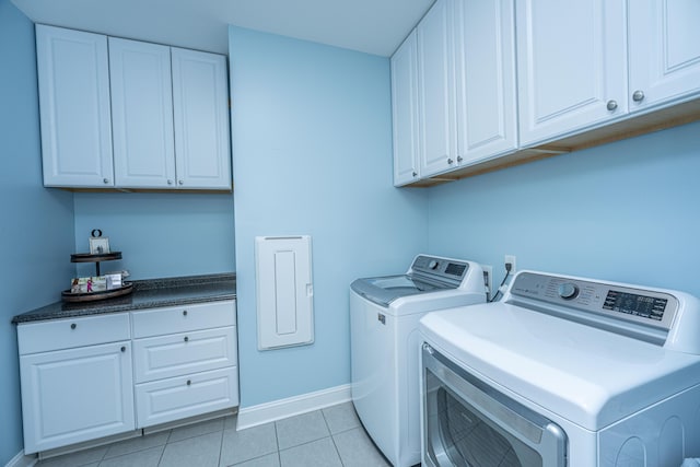 laundry area featuring light tile patterned floors, washer and clothes dryer, and cabinets