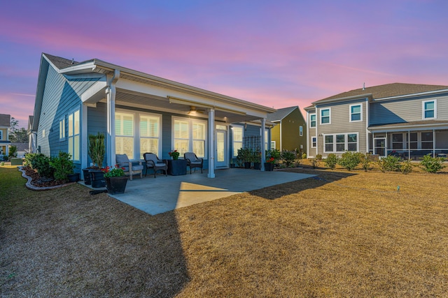 back house at dusk with a yard and a patio