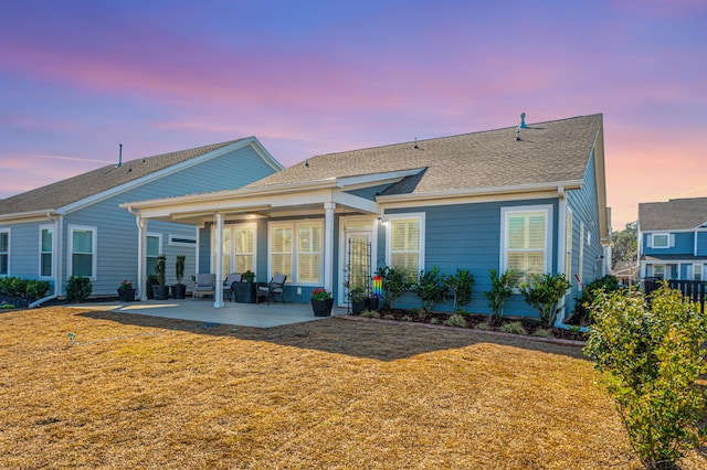 back house at dusk featuring a yard and a patio