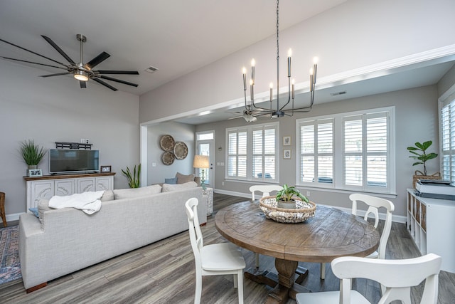 dining room with lofted ceiling, ceiling fan with notable chandelier, and light hardwood / wood-style floors