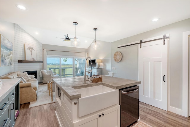 kitchen featuring pendant lighting, sink, black dishwasher, white cabinets, and a barn door