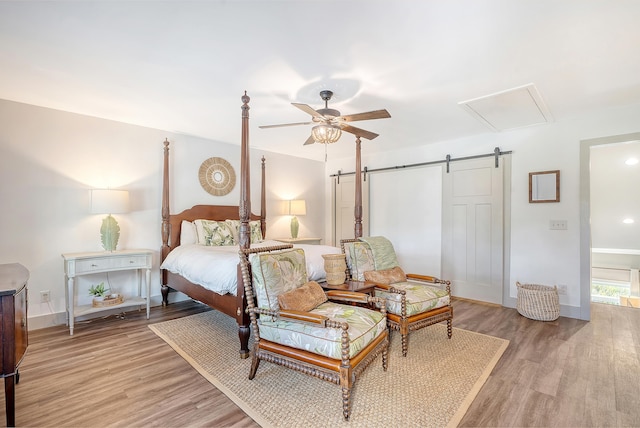 bedroom featuring a barn door, ceiling fan, and light hardwood / wood-style flooring