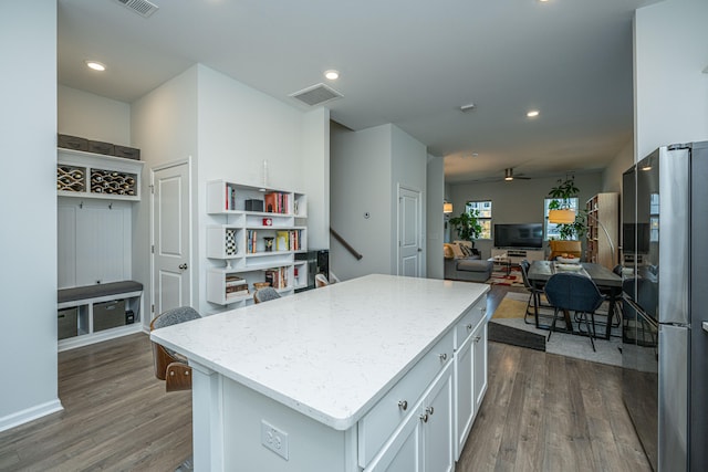 kitchen featuring ceiling fan, a kitchen island, white cabinetry, dark hardwood / wood-style floors, and black refrigerator