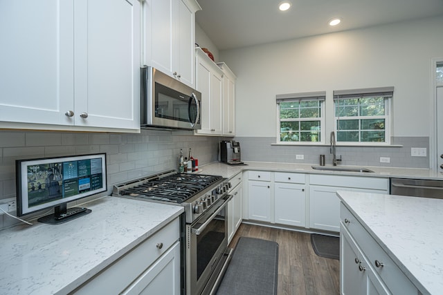 kitchen with white cabinets, light stone counters, appliances with stainless steel finishes, dark hardwood / wood-style floors, and sink