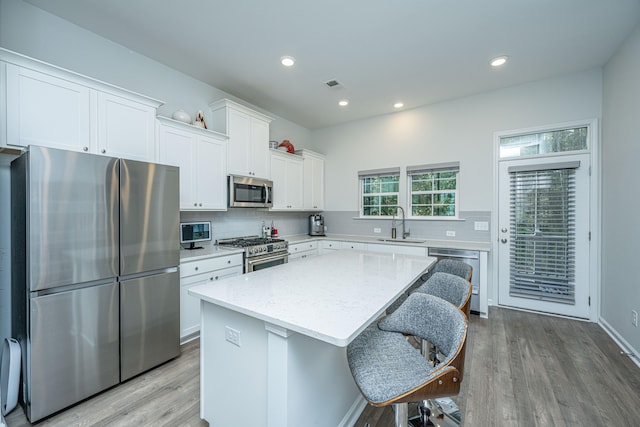 kitchen featuring appliances with stainless steel finishes, light hardwood / wood-style flooring, white cabinetry, and a center island